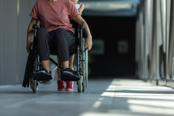 A person in a wheelchair being supported through a hallway